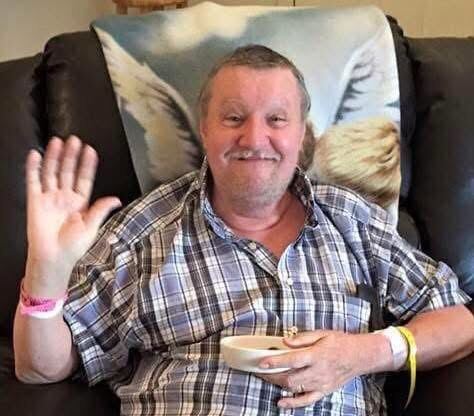 In loving memory — a cherished smile, hand raised in greeting.